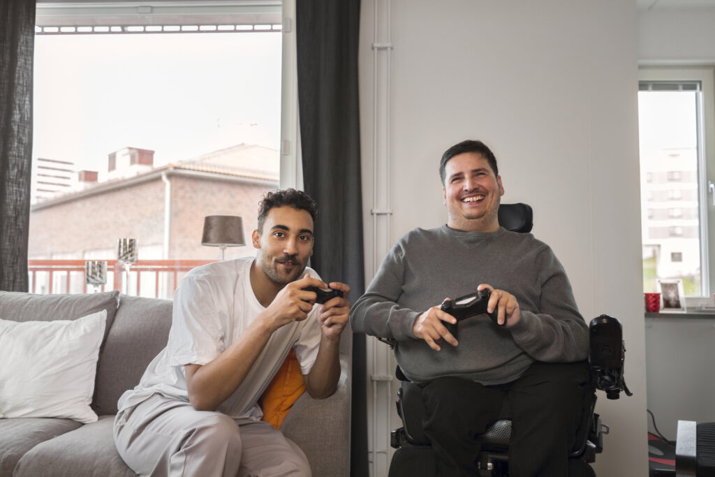 A disabled man playing vedio games with support worker